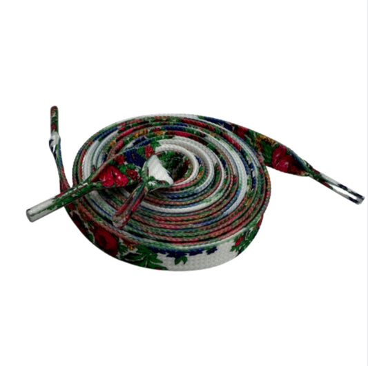 A pair of white shoe laces with red floral patterns, coiled together.
