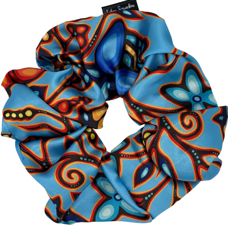 A light blue satin scrunchie with a colorful pattern, displayed on a white background