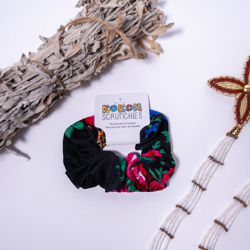 floral scrunchie on a white background with a kokom scrunchies tag, with a bundle of sage to the left and beaded earrings on the right