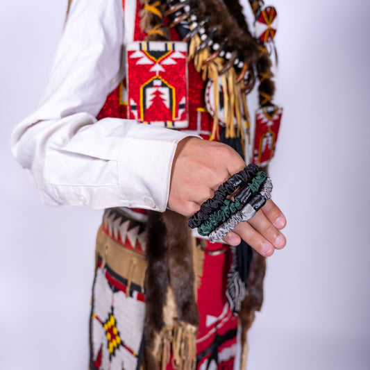 Person wearing a colorful regalia holding mini scrunchies against a white background