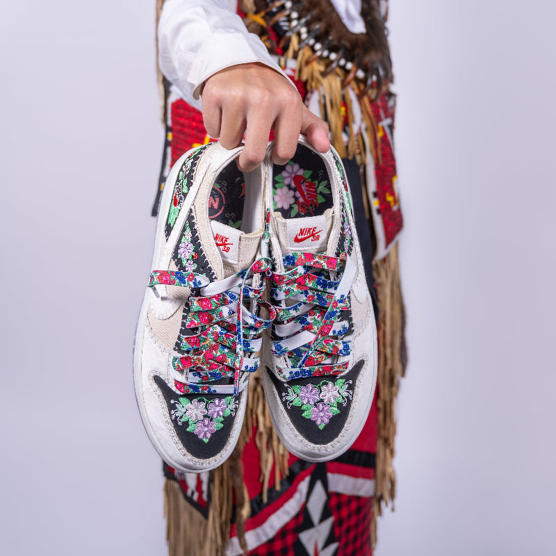 Person holding a pair of sneakers with kokom laces and a white background