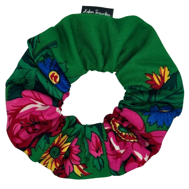 A green scrunchie with a floral pattern consisting of pink, yellow, and blue flowers.