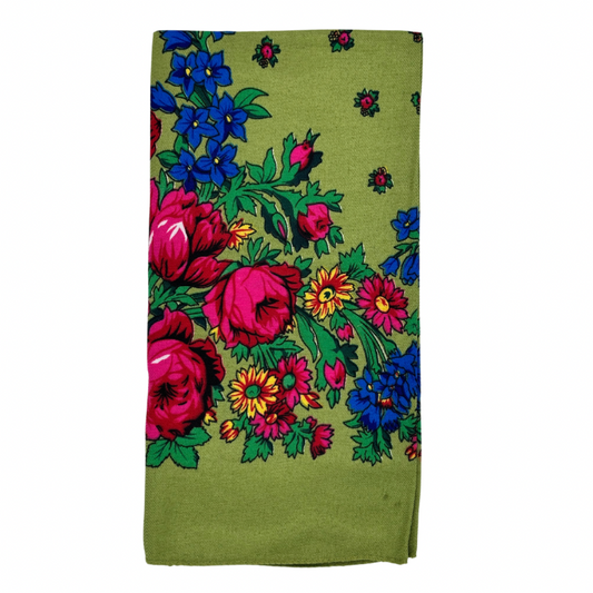 A light green scarf with a floral pattern, including large pink and blue flowers, folded neatly.