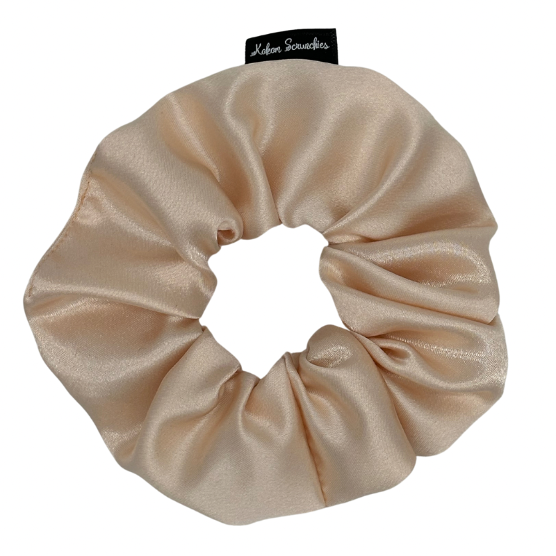 A light peach satin scrunchie displayed on a plain background.