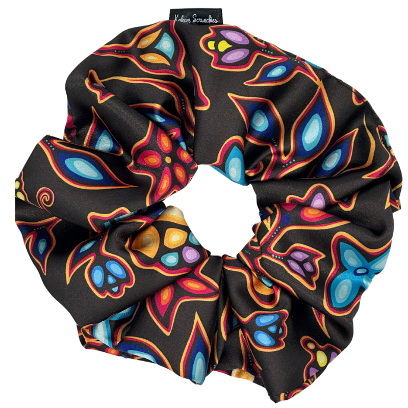 A large black satin hair scrunchie with a colorful geometric pattern.