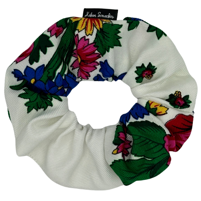 A white hair scrunchie with a colorful floral pattern.