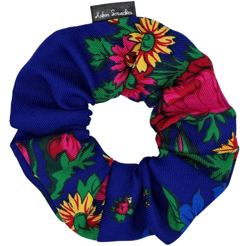 A royal blue scrunchie with a bright multicolor floral pattern.