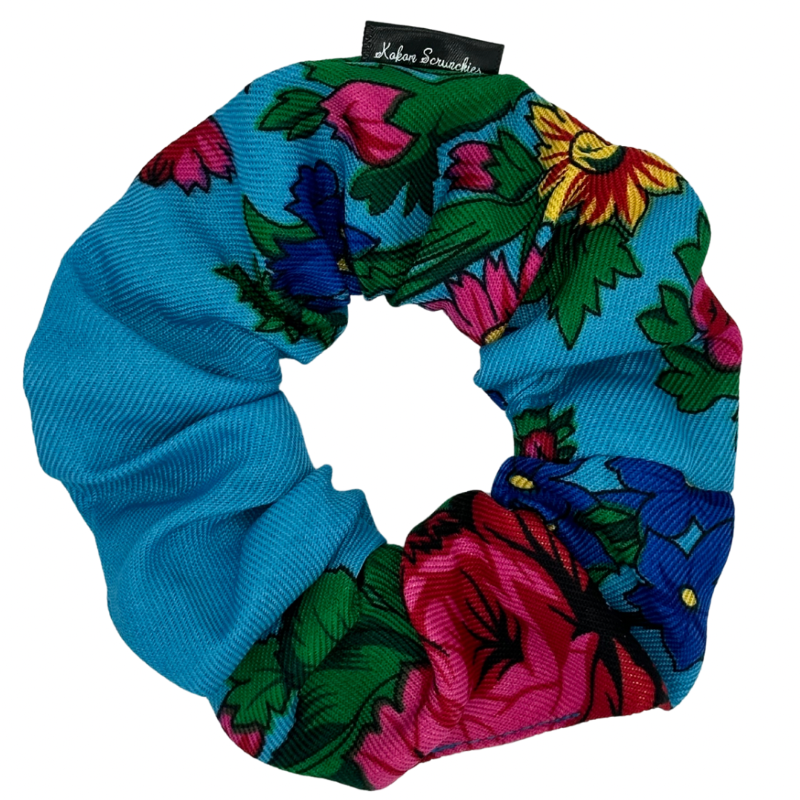 A light blue scrunchie with a floral pattern consisting of various flowers in different colors.
