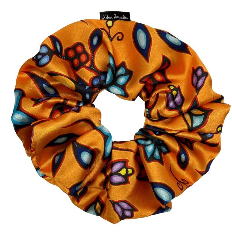 A satin ponytail holder with a light orange base and a multicolored floral pattern.