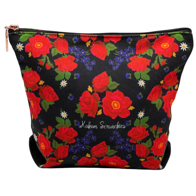 A black cosmetic bag with a floral pattern featuring red roses and smaller green and white flowers, branded with 'Kokom Scrunchies'.
