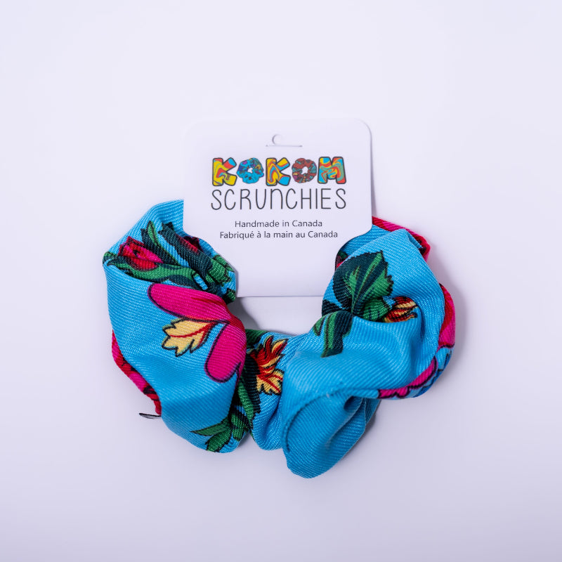 blue scrunchie with floral designs on a white background, featuring a 'Kokom Scrunchies' label.