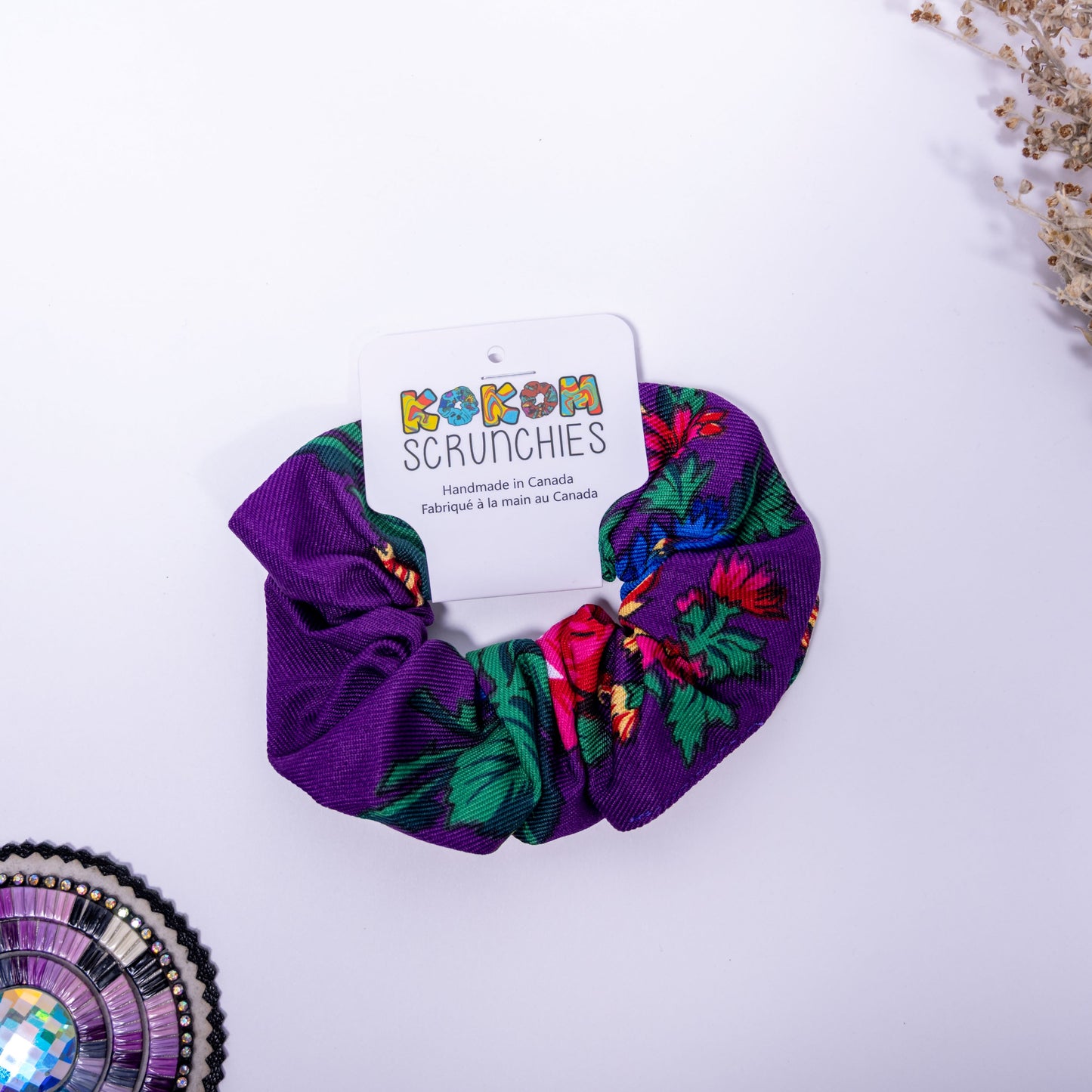purple scrunchie with floral patterns on a white background, featuring a 'Kokom Scrunchies' card.