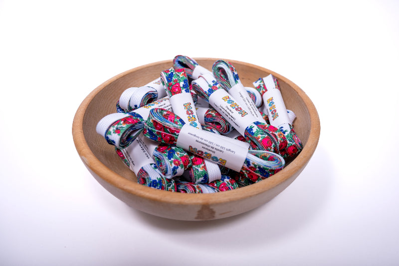 Wooden bowl filled with shoe laces on a white background